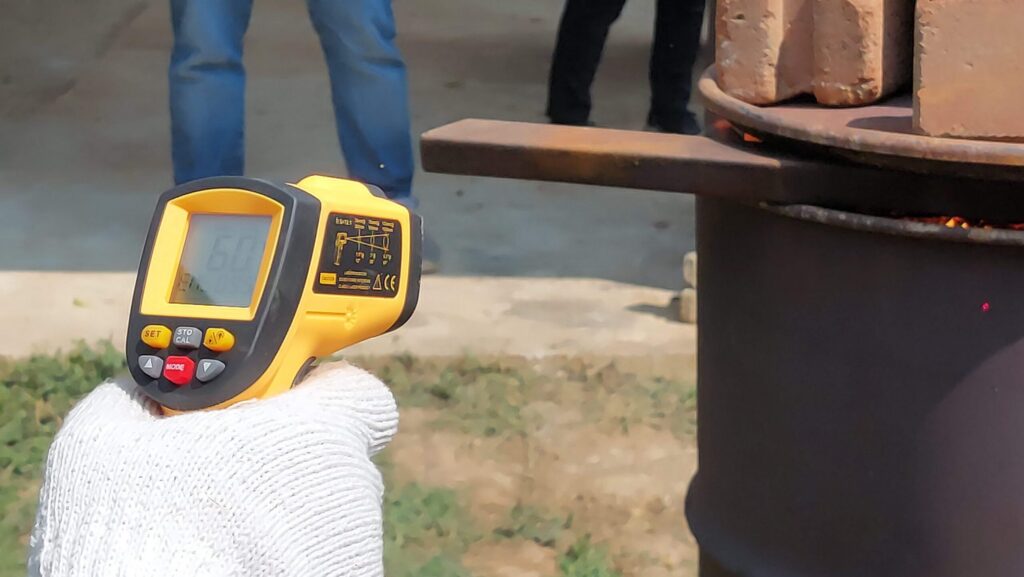 Monitoring pyrolysis process with a digital temperature gun to ensure proper biochar production conditions.